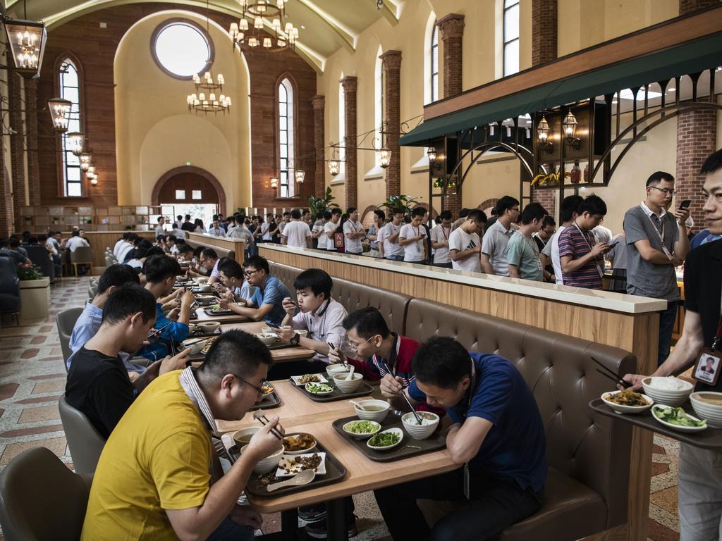 Huawei workers eat lunch as others line-up at one of several cafeterias. Picture: Getty