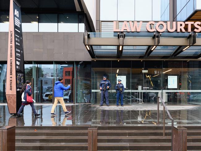 Members of the Muslim community walk past armed police officers at Christchurch High Court this morning. Picture: Getty