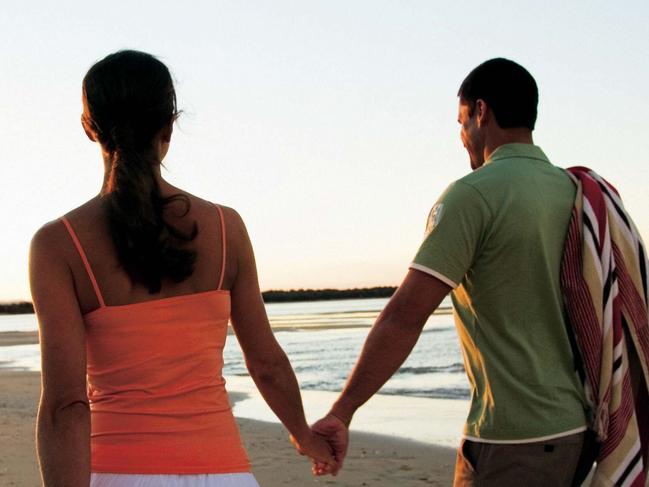 Undated : generic couple holding hands as they walk along the beach at sunset