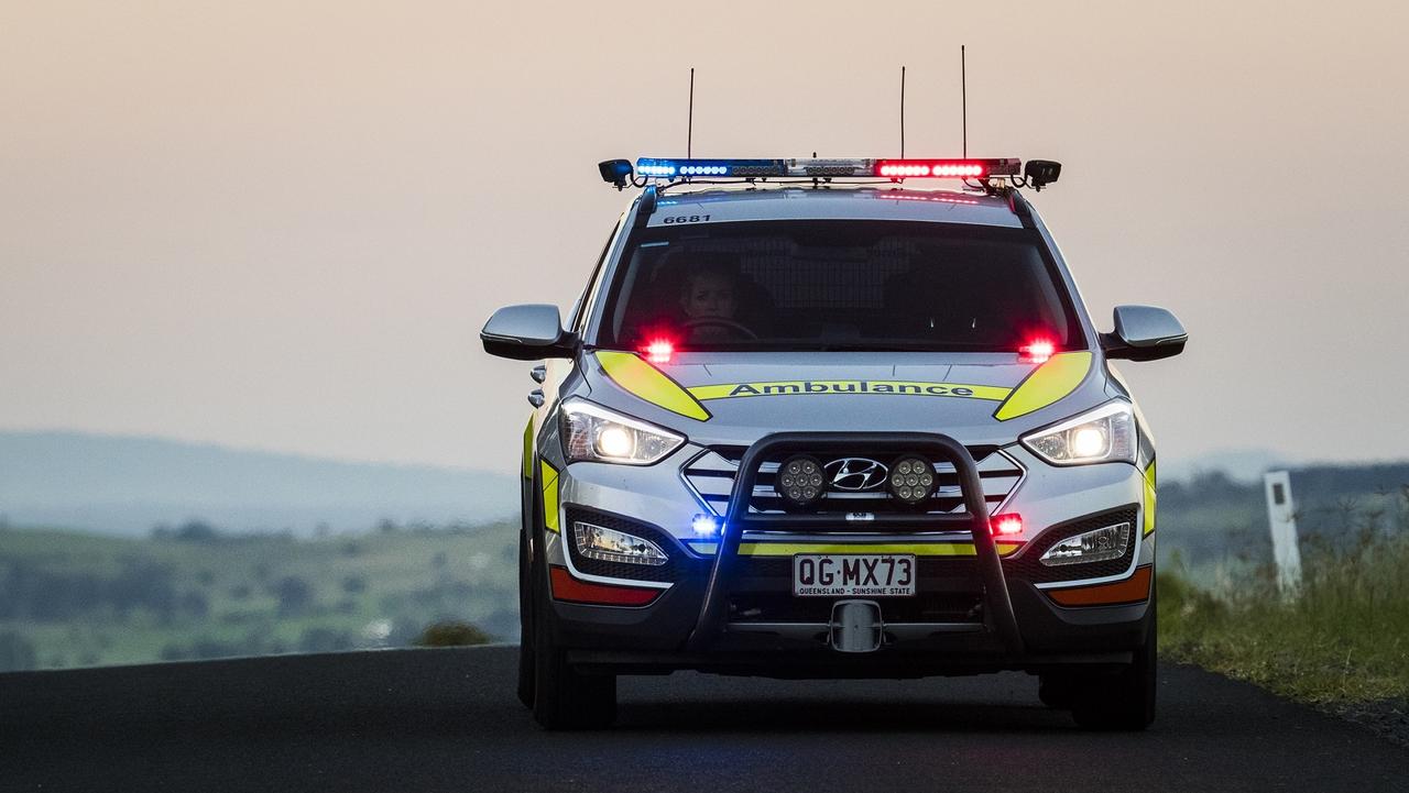 Queensland Ambulance Service paramedics a treating a man injured in a single-vehicle crash.