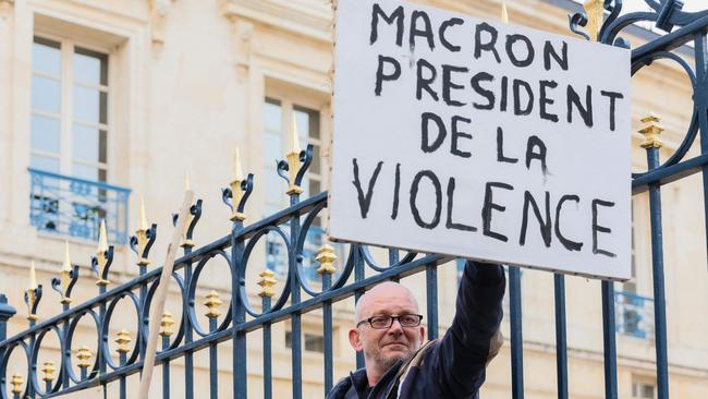 A protester holds a placard reading "Macron president of the violence" in front of the Deux-Sevres prefecture.