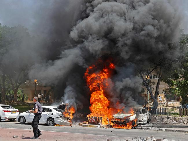 TOPSHOT - Vehicles are pictured ablaze after a rocket launched from the Gaza Strip, controlled by the Palestinian Hamas movement, landed in the southern Israeli city of Ashkelon on May 11, 2021. - Israel and Hamas exchanged heavy fire, in a dramatic escalation between the bitter foes sparked by unrest at Jerusalem's flashpoint Al-Aqsa Mosque compound. (Photo by JACK GUEZ / AFP)