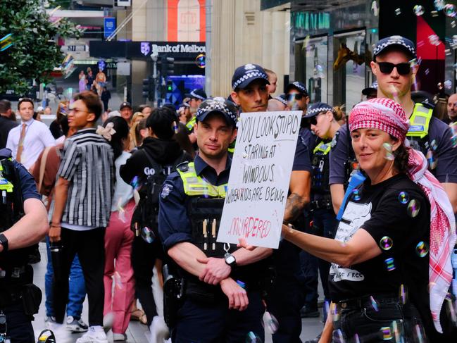 One held a sign saying ‘you look stupid staring at windows while kids are being murdered’. Picture: NewsWire / Luis Enrique Ascui