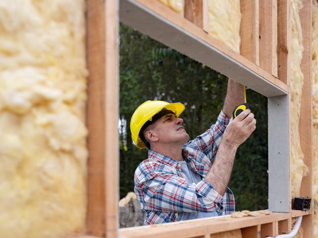 Construction worker taking measurements while building a house with insulation