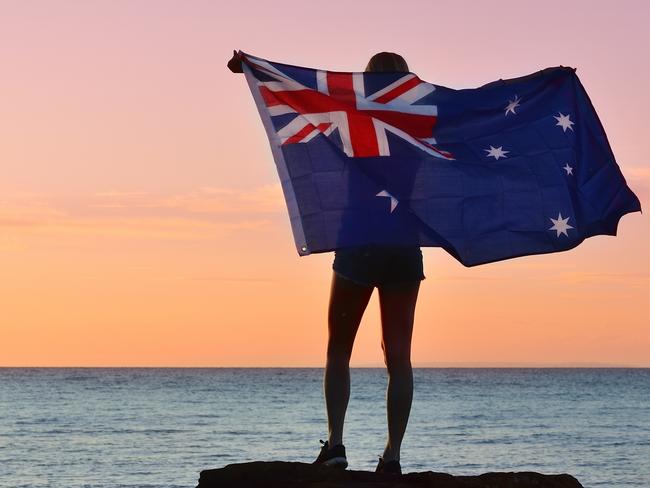 Waving the Australian Flag, evening summer light on a beach.