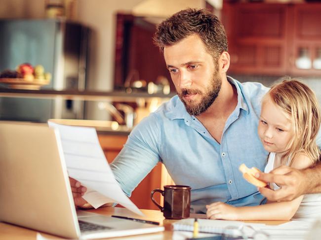 Coronavirus.  Picture: istock Close up of a father checking his financials while his daughter has breakfast and while he is working from home. Picture: iStock.