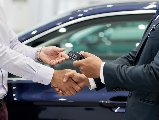 Salesman giving car keys to customer and shaking his hand