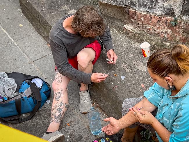 A man and a woman openly inject drugs along the Southbank boulevard near corner of Queens Bridge street and Sandridge Bridge (footbridge) at one point they watch children play at a gaming installation just meters away.  Southbank drug taking and anti social behaviour. (VIDEO AVAILABLE) Picture: Jason Edwards