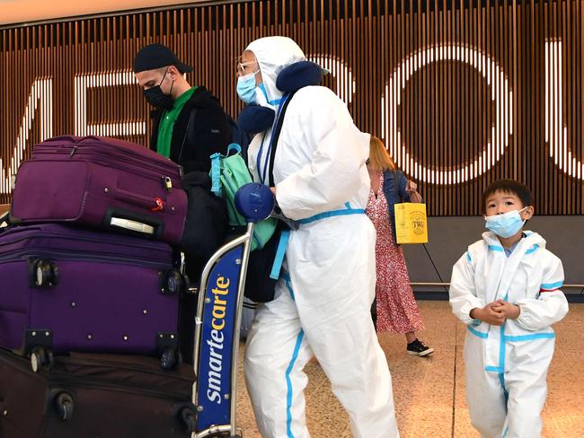 TOPSHOT - International travellers wearing personal protective equipment (PPE) arrive at Melbourne's Tullamarine Airport on November 29, 2021 as Australia records it's first cases of the Omicron variant of Covid-19. (Photo by William WEST / AFP)