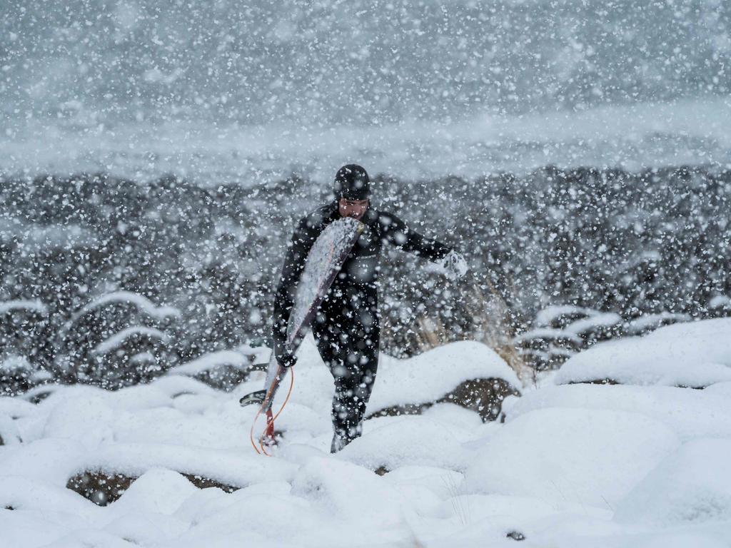 A surfer walks out of the water under snowfall, on March 11, 2018, in Unstad, northern Norway, Lofoten islands, within the Arctic Circle. Picture: AFP