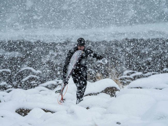 A surfer walks out of the water under snowfall, on March 11, 2018, in Unstad, northern Norway, Lofoten islands, within the Arctic Circle. Picture: AFP