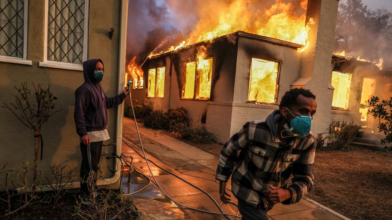 Samuel Girma runs to get another hose as he helps try to prevent a home from catching fire on LaPaz Rd as the Eaton Fire continues to grow. Picture: Getty