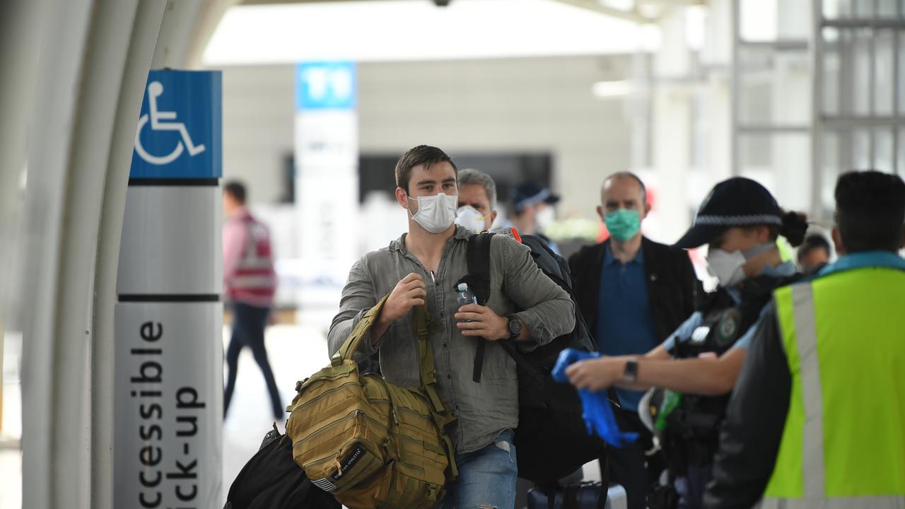 A member of the Defence Force watches over as returning overseas travellers are ushered towards waiting buses for the beginning of their 14-day quarantine after arriving at Sydney Airport today. Picture: Joel Carrett