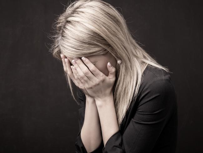 Woman holding her face in her hands. istock image