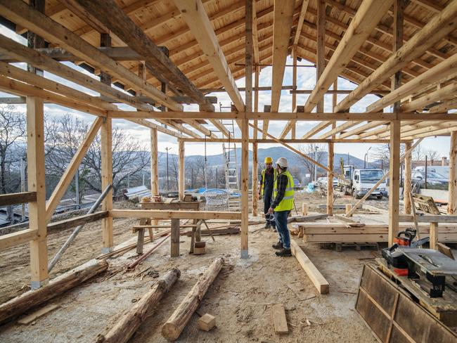 Construction workers in building site of wooden house.