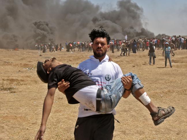 A Palestinian carries an injured protester during clashes with Israeli forces over the US embassy move to Jerusalem on May 14. Picture: AFP