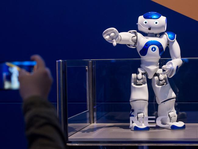 A visitor takes a picture of NEC's NAO robot during the Mobile World Congress on the third day of the MWC in Barcelona, on March 1, 2017. Phone makers will seek to seduce new buyers with artificial intelligence functions and other innovations at the world's biggest mobile fair starting today in Spain. / AFP PHOTO / Josep Lago