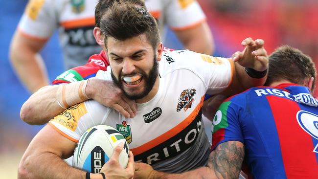 NEWCASTLE, AUSTRALIA - MAY 17: James Tedesco of the Tigers is tackled by the Knights defence during the round 10 NRL match between the Newcastle Knights and the Wests Tigers at Hunter Stadium on May 17, 2015 in Newcastle, Australia. (Photo by Tony Feder/Getty Images)