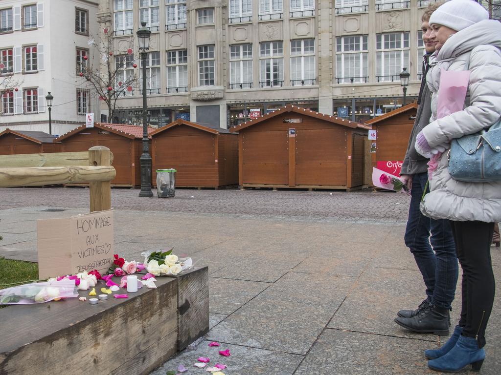 A couple put flowers at the Christmas market where the day before a man shot 14 people, killing at least two. Picture: Getty