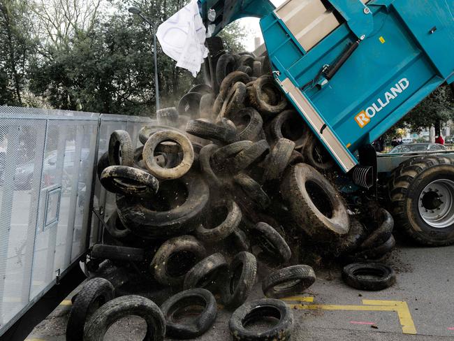 French farmers unloaded a pile of tyres in front of the city administrative center in Lyon, on February 22, 2021 during a demonstration to protest against the city majority's decision to keep meat off city schools' menu to, the mayor said, "ensure a smooth service at lunchtime during the social distancing enforced by the Covid-19 pandemic". (Photo by OLIVIER CHASSIGNOLE / AFP)