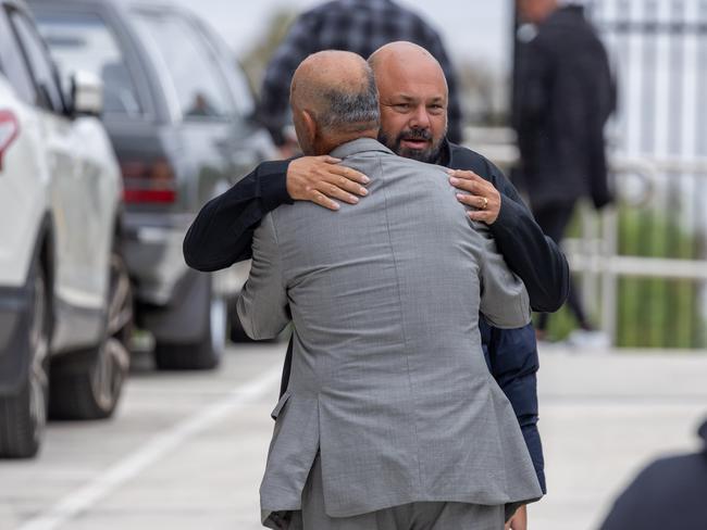 Mourners embrace outside the service.