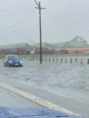 A car goes through a flooded Milperra Rd on Sunday. Picture: Jess Rae Morris