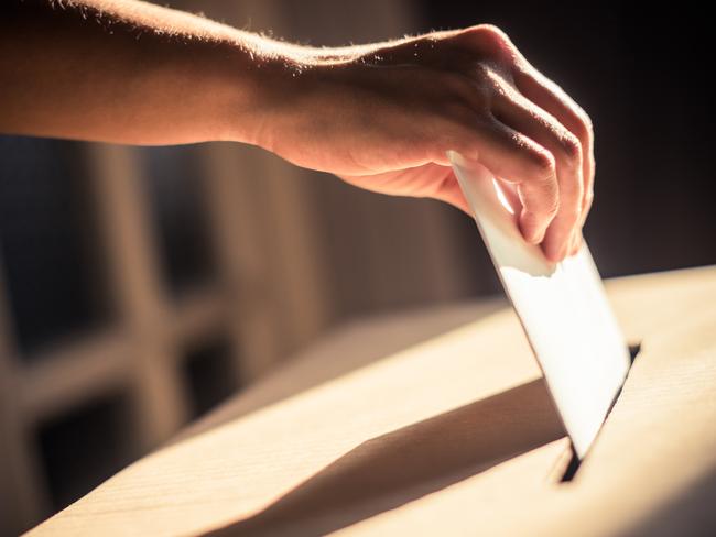 Conceptual image of a person voting, casting a ballot at a polling station, during elections.