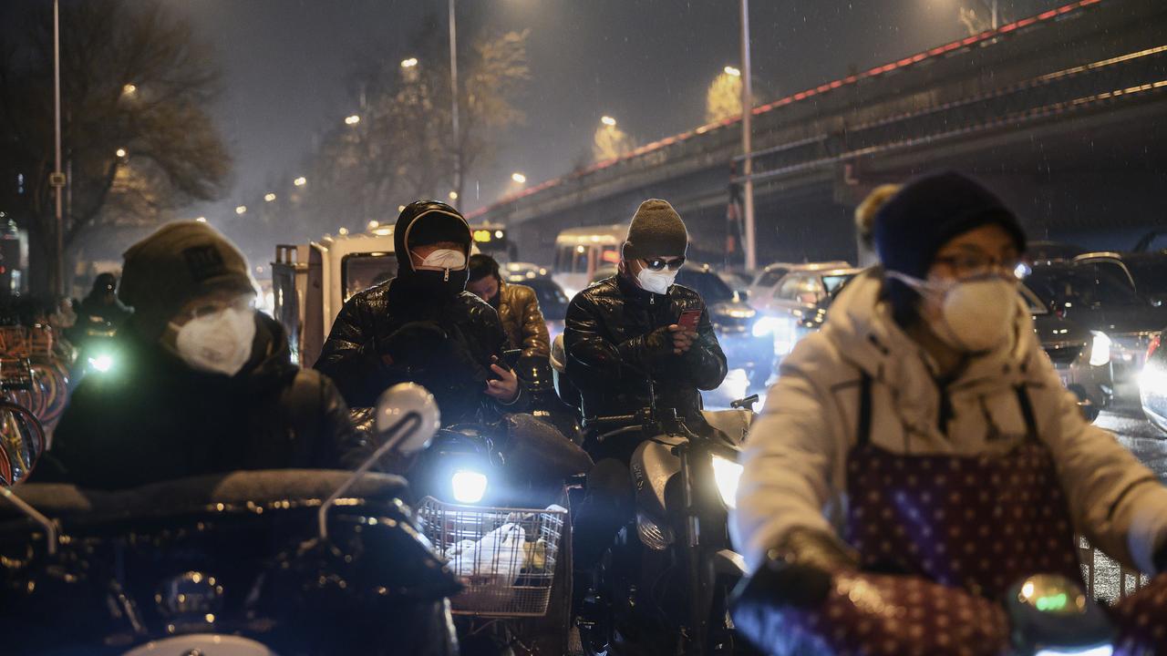 Chinese commuters wear protective masks while waiting at a light in the rain during the evening rush hour in Beijing, China. Picture: Kevin Frayer/Getty Images