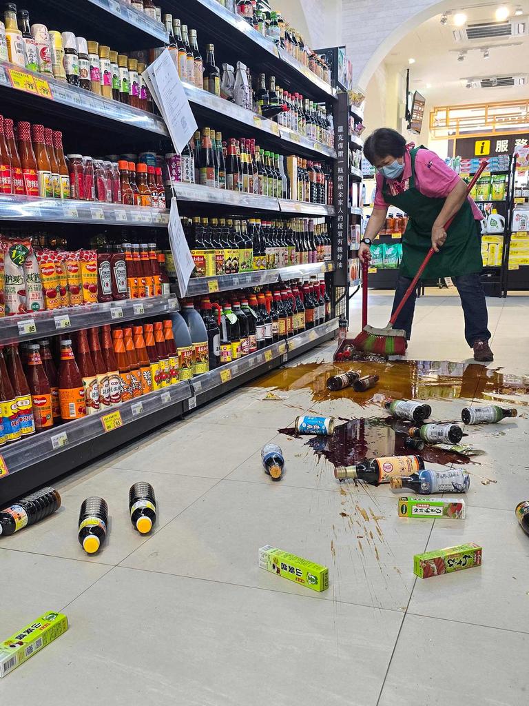 A shop employee clears broken bottles on the floor of a supermarket in Yilan, after a major earthquake hit Taiwan's east. Picture: CNA / AFP