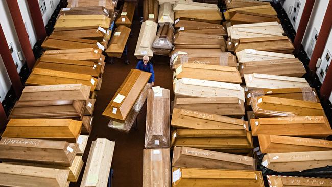 An employee moves coffins, some marked with "infection risk" as others have "corona" scrawled in chalk, in the mourning hall of the crematorium in Meissen, eastern Germany last month. Picture: AFP