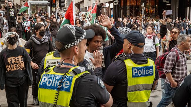 Police officers stand guard as protesters march in Melbourne. Picture: NewsWire.