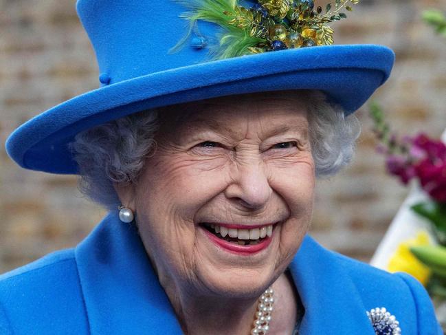 (FILES) In this file photo taken on October 11, 2019 Britain's Queen Elizabeth II reacts as she visits the Haig Housing Trust in Morden, southwest London, to open their new veteran housing development. - Brightly coloured outfits, a matching hat and a pristine pair of gloves: Queen Elizabeth II's look was instantly recognisable and a self-created uniform styled to suit her role. During her reign, the monarch tried out every shade in the colour chart, from canary yellow to lime green, fuchsia and navy blue. Her inimitable style was developed over the decades by aides and designers, starting with Norman Hartnell, who created her wedding dress when she married Prince Philip in 1947. (Photo by Jack Hill / POOL / AFP)