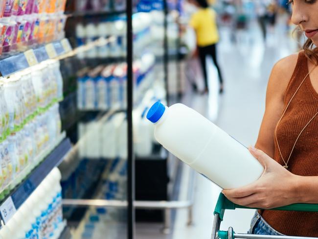 Young woman checking milk's labeling in supermarket