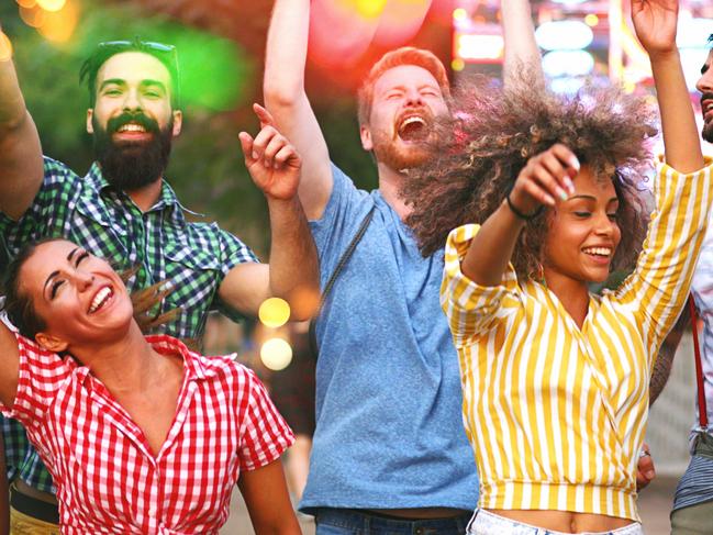 Closeup of group of multi ethnic young adults dancing and enjoying an open air concert on a summer afternoon. There are three girls and three guys dancing and jumping like there's no tomorrow.