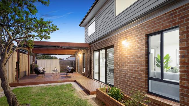 A sliding-glass door leads to the north-facing rear garden with an undercover deck featuring cafe blinds and grassy areas.