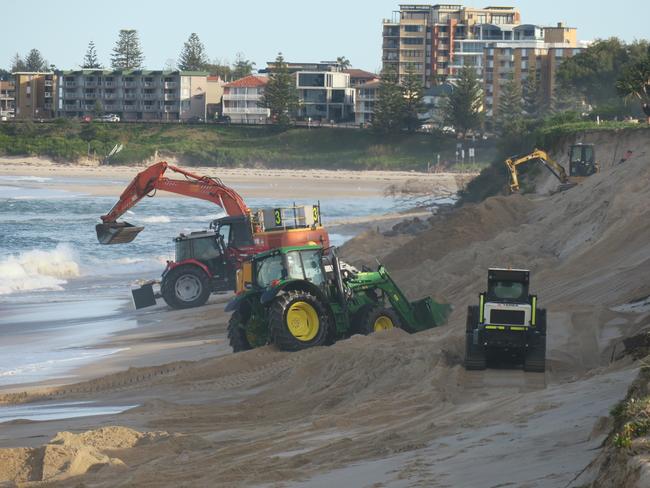 Excavators, Bobcats and tractors at The Entrance North moving sand back up the beach where erosion has washed it away. Picture: Richard Noone