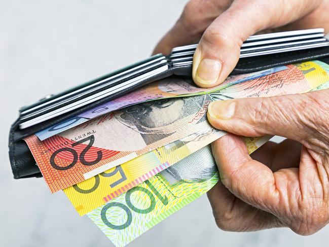 Close-up, senior female hands taking Australian banknotes (cash, currency) from purse containing many credit cards.  Horizontal, studio, copy space. Money generic