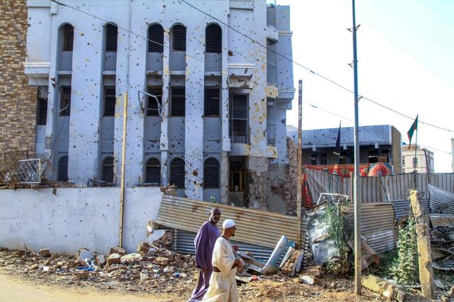 Sudanese pass a bullet-riddled building in Khartoum's twin-city Omdurman -- the military has regained ground from paramilitaries in the Khartoum area