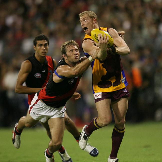 24/02/2006. Michael Voss handballs away from opponent Mark McVeigh. Brisbane Lions vs Essendon at Carrara on the Gold Coast. NAB Cup.