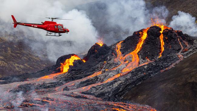 A chopper on Sunday flies close to the volcanic eruption in a valley near Mount Fagradalsfjall, just 40km from Reykjavik. Picture: Getty Images