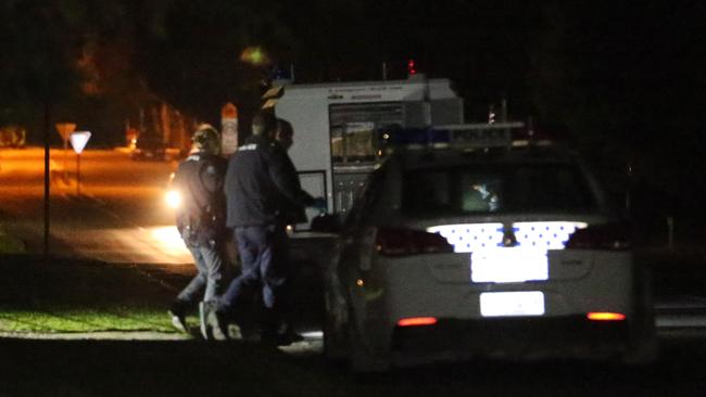 The suspect is led to a police car at 9:12pm after the incident in Goolwa. Picture: Stephen Laffer