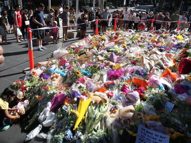 People continue to lay flowers in Bourke St on Sunday evening. Picture: David Crosling