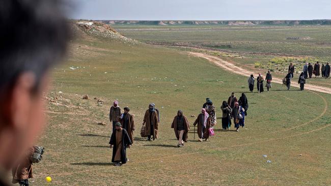 Men believed to be Islamic State fighters and their families walk in a field as they leave the IS' embattled holdout of Baghouz during an operation by the US-backed Syrian Democratic Forces (SDF). Picture: AFPs