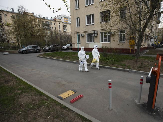 Doctors, wearing special suits to protect against coronavirus, walk after they visit a person suspected of having the virus at an apartment building in Moscow. Picture: AP