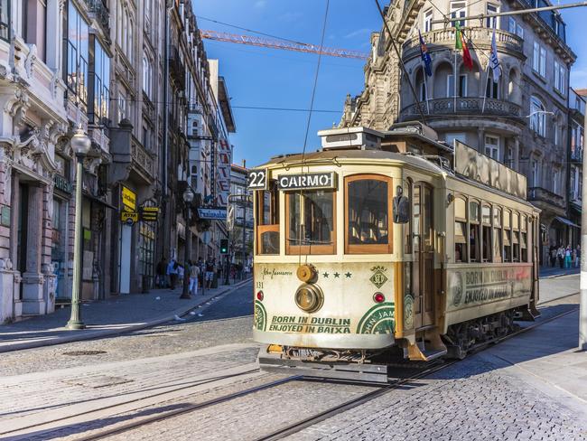 Porto, Portugal - April 24, 2016: Electric tram going past in Porto city centre, Portugal. Buildings and historic architecture in the old city centre. Many tourists in this city at the Ribeira district, near the Douro riverside. Photo: iStock