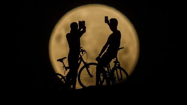 PERTH, AUSTRALIA - JANUARY 31:  Photo Illustration showing people with bicycles taking photos of the Super moon on January 31, 2018 in Lancelin, Australia. Last seen from Australia in December 1983, a Super Blue Blood Moon is the result of three lunar phenomena happening all at once. Not only is it the second full moon in January, but the moon will also be close to its nearest point to Earth on its orbit, and be totally eclipsed by the Earth's shadow.  (Photo by Paul Kane/Getty Images)