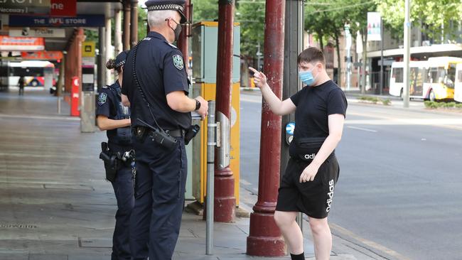 Police hand out masks on the streets of Adelaide on the first day of lockdown. Picture: Tait Schmaal.