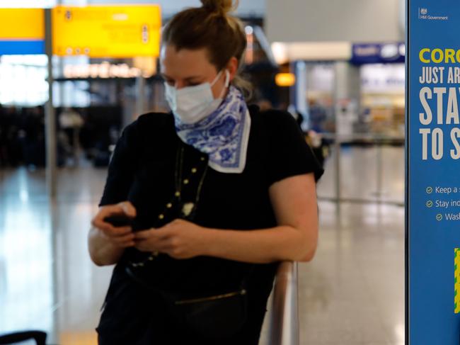 A passenger wearing PPE (personal protective equipment) checks her phone on arrival at Terminal 2 of Heathrow airport, west London on May 22, 2020. (Photo by Tolga Akmen / AFP)