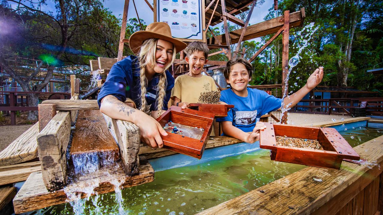 Madi Roberts (left) helps Ishai, 9 and Jonah Angel, 14, search for gemstones at the new Currumbin Wildlife Sanctuary precinct Outback Springs. Picture: Nigel Hallett