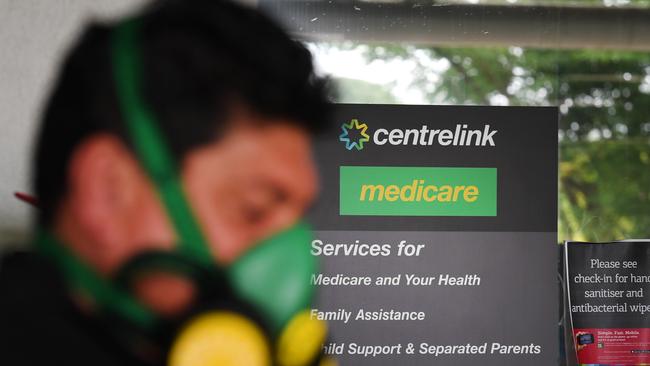 A man wearing a face mask is seen queuing outside the Centrelink office in Southport. (AAP Image/Dan Peled)